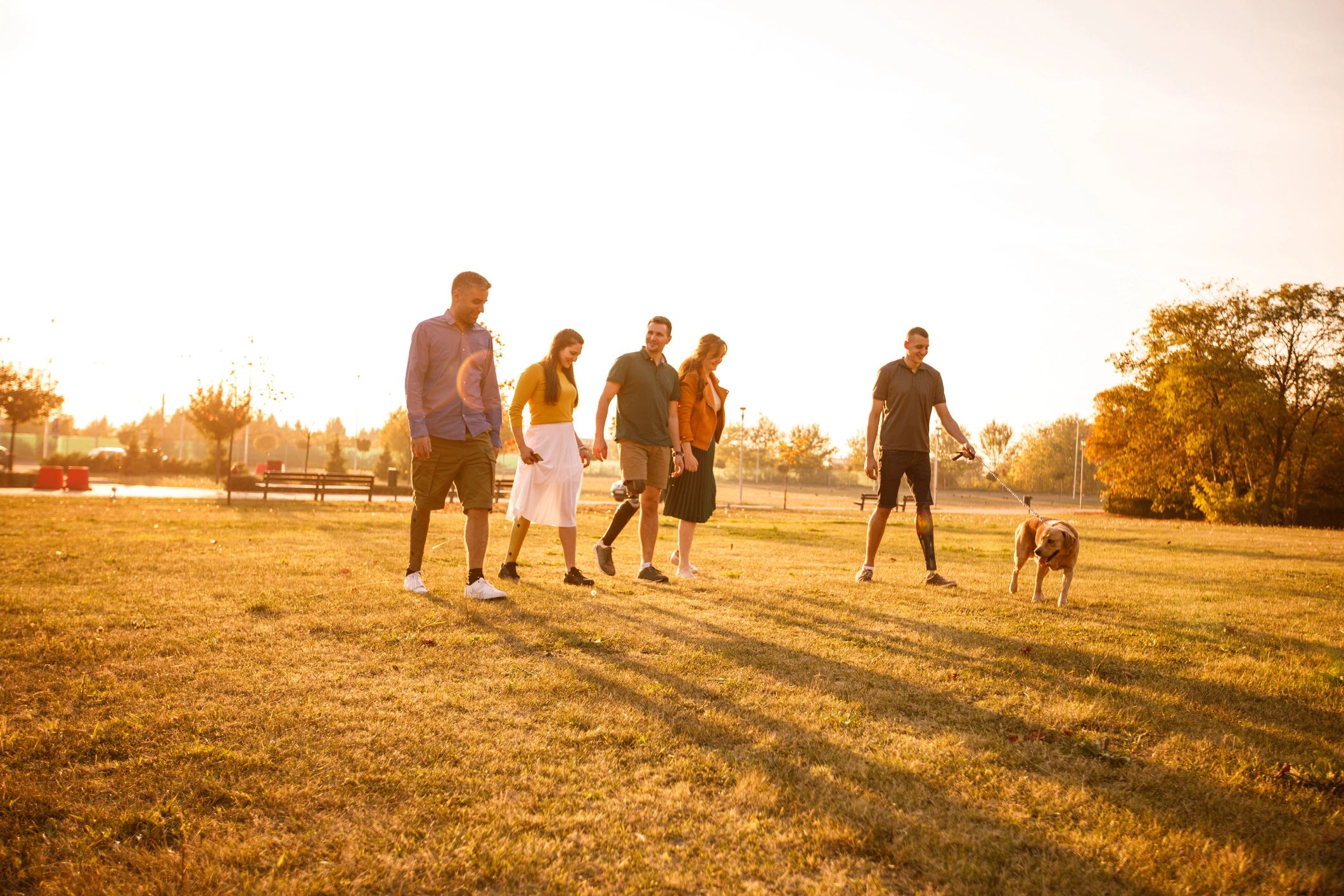 People walking together across a grassy park at sunset